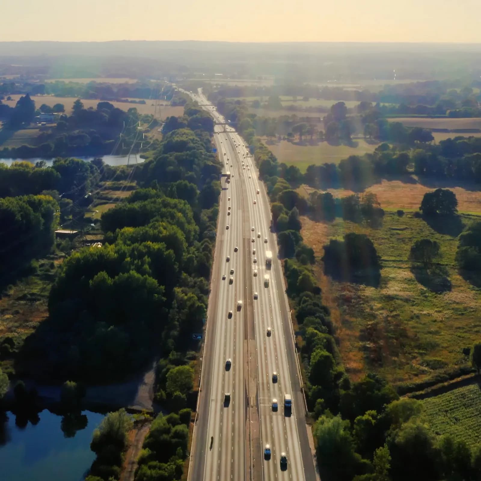 Aerial shot of a motorway at sunset surrounded by green countryside