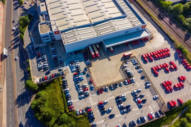 Aerial view of a Royal Mail postal delivery depot with rows of red last-mile vans parked in the yard