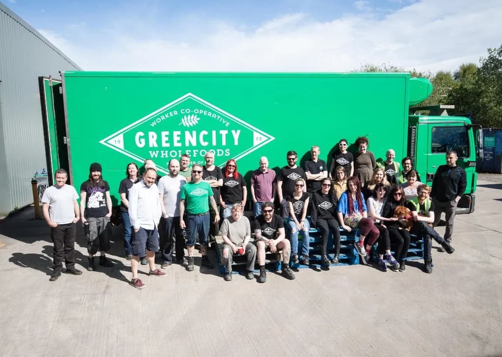 Greencity Wholefoods worker co-operative team photographed in front of their branded green delivery HGV