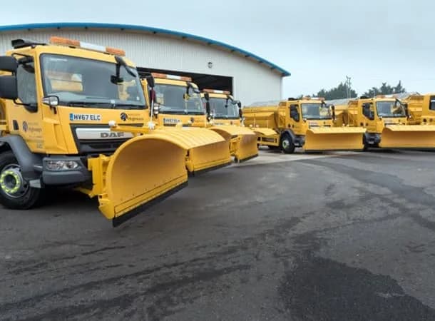 Yellow Hampshire Highways DAF gritters with snowploughs lined up outside a depot