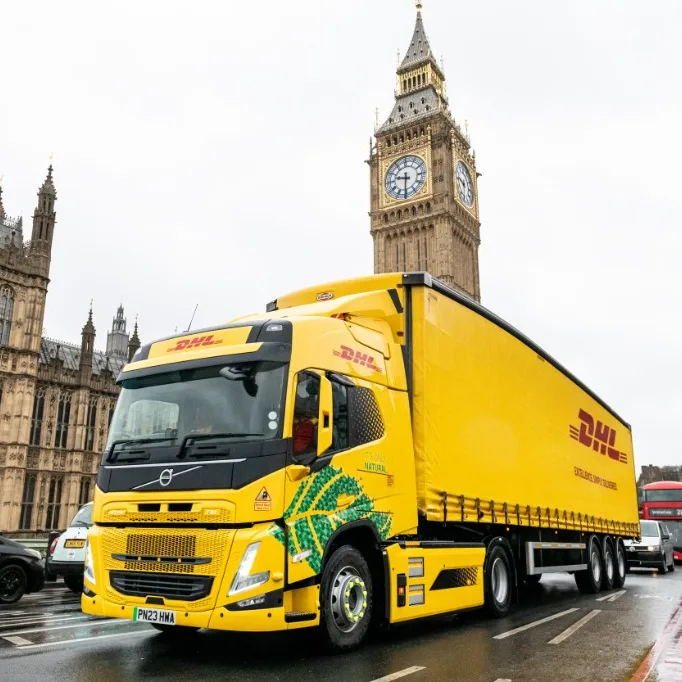 DHL yellow Volvo FM electric heavy goods vehicle passing the Palace of Westminster and Big Ben in London