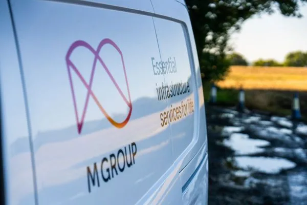 White M Group van with the line Essential infrastructure services for life, parked beside a wet lane